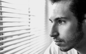 Hombre mirando por la ventana triste en blanco y negro